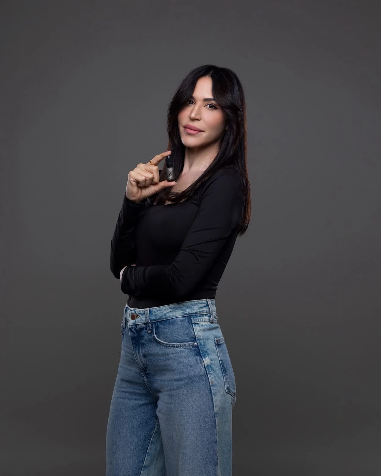 מיטל אבוהב בחולצה שחורה וג'ינס על רקע אפור, מדריכת השתלמות פיגמנט שפתיים